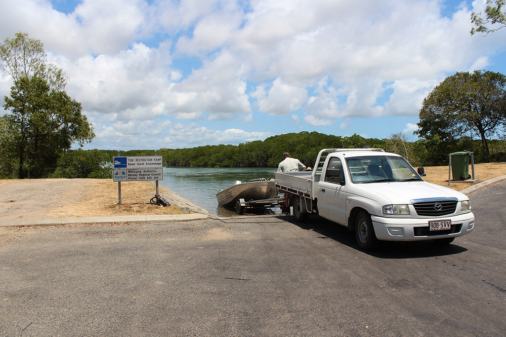 A vehicle launching an aluminium boat to the lake on a concrete boat ramp.