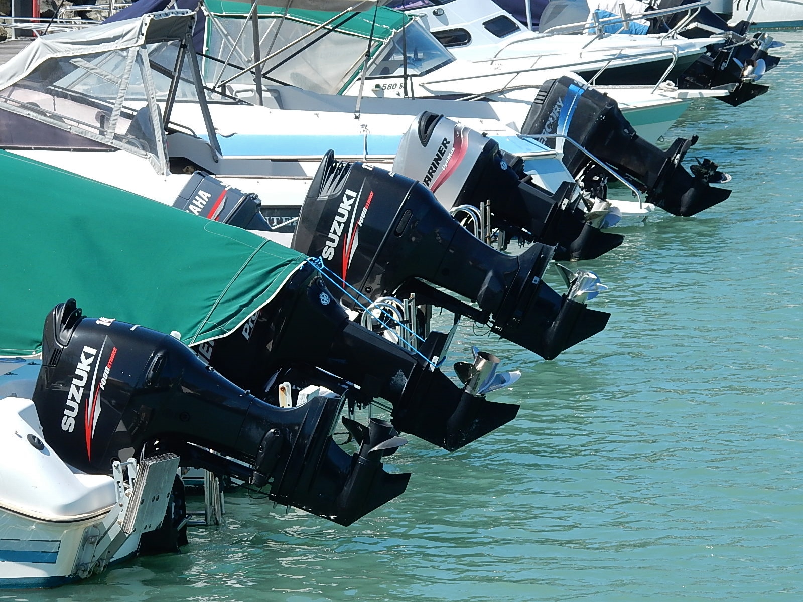 Aluminium boats with Suzuki engines docked in a marina.