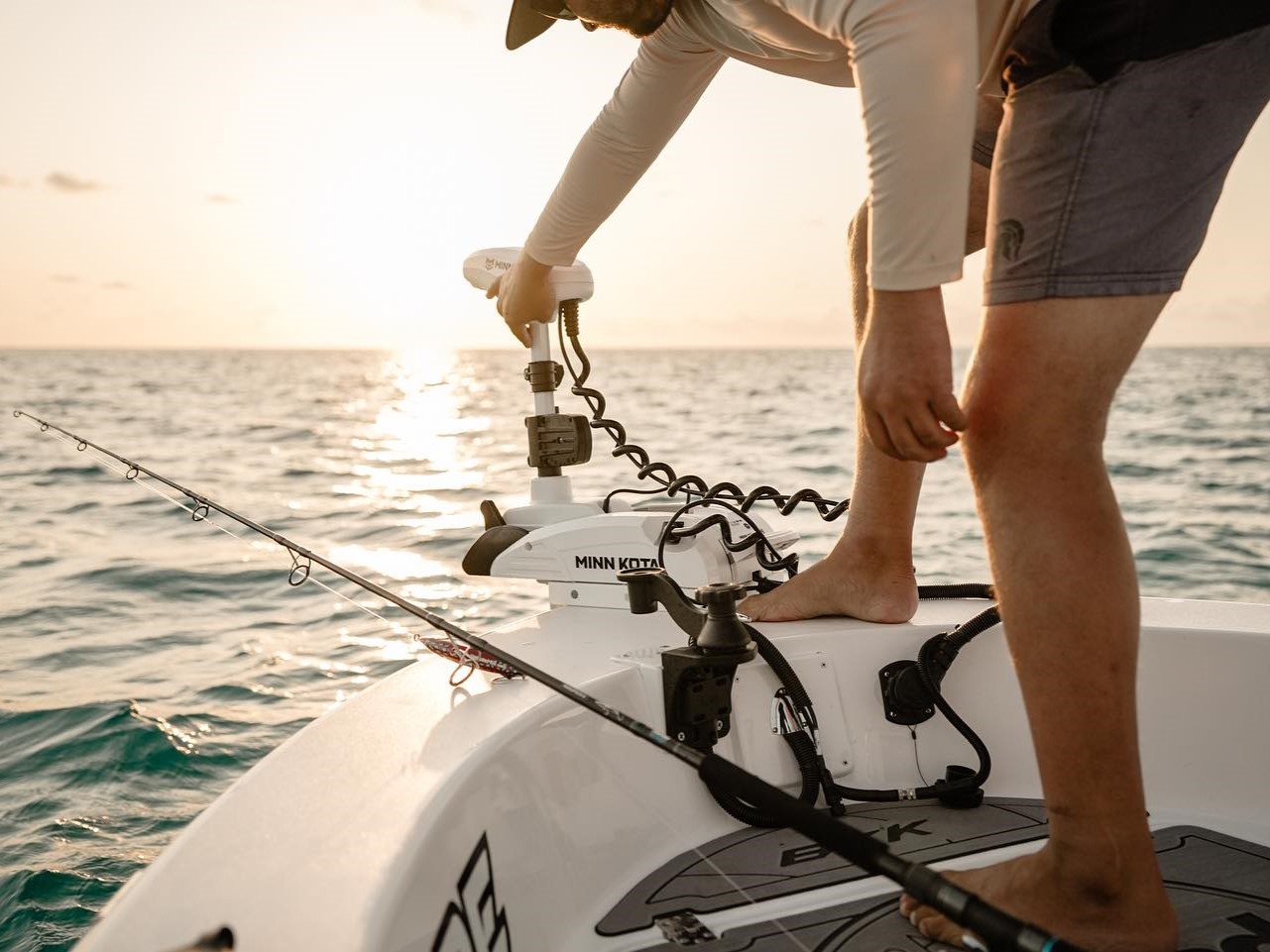a person holding a minn kota trolling motor that is installed on the front of a boat