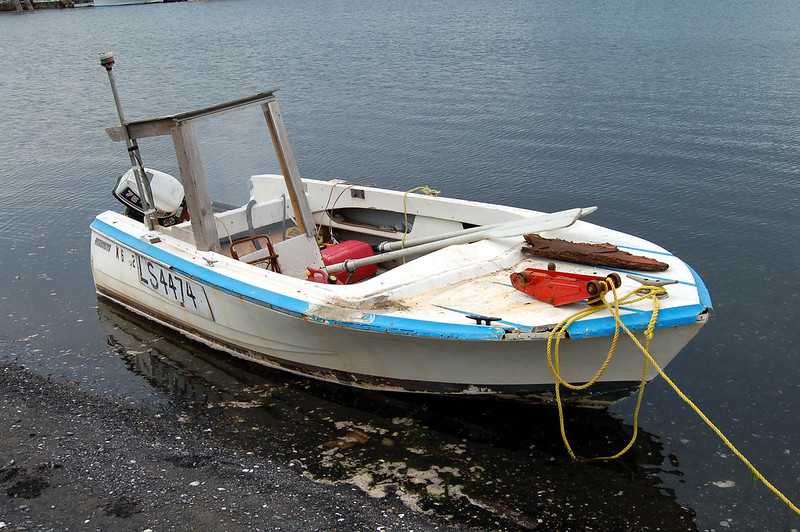 An old and small open boat beached in a shore.