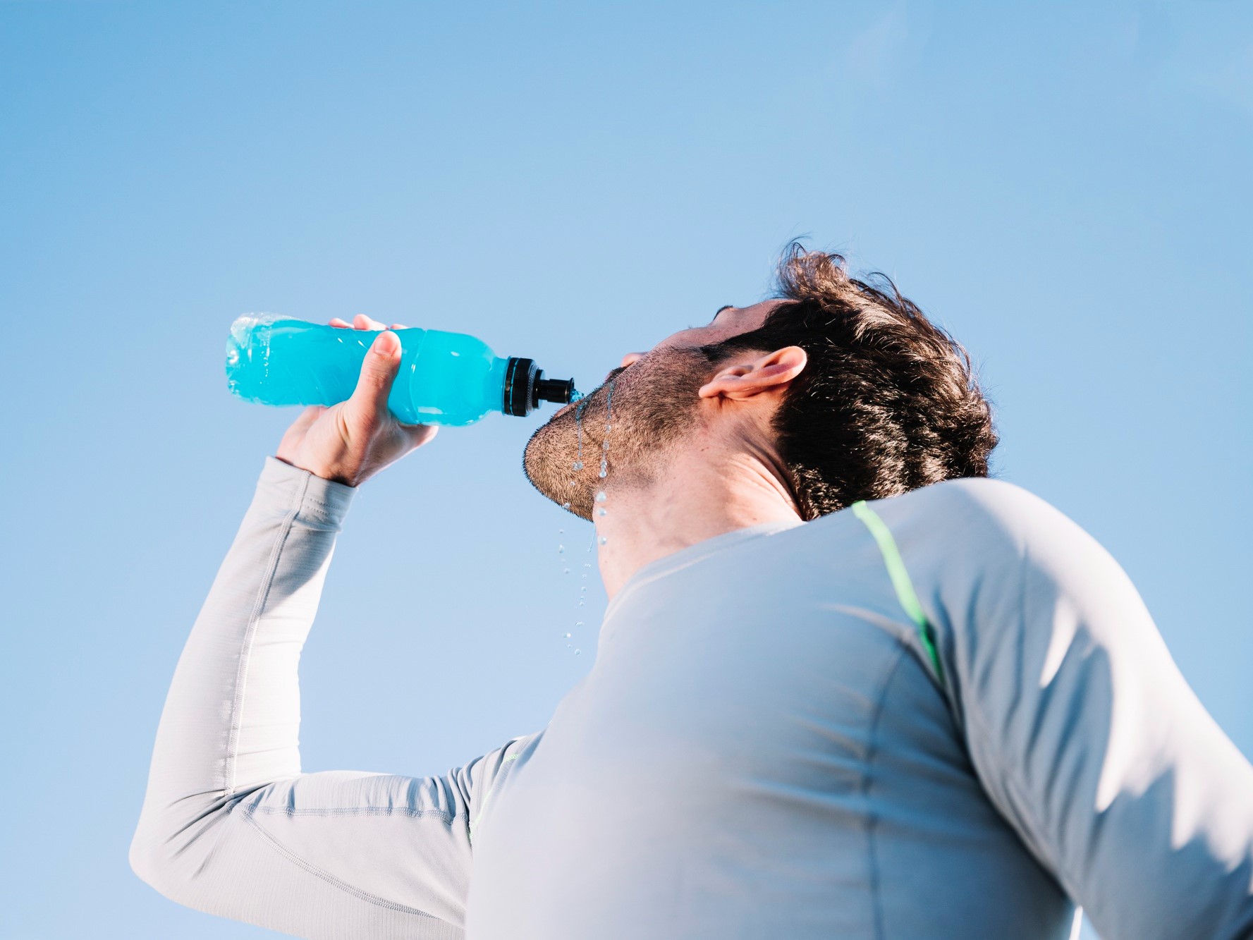 man staying hydrated by drinking fluids while being out during a sunny day