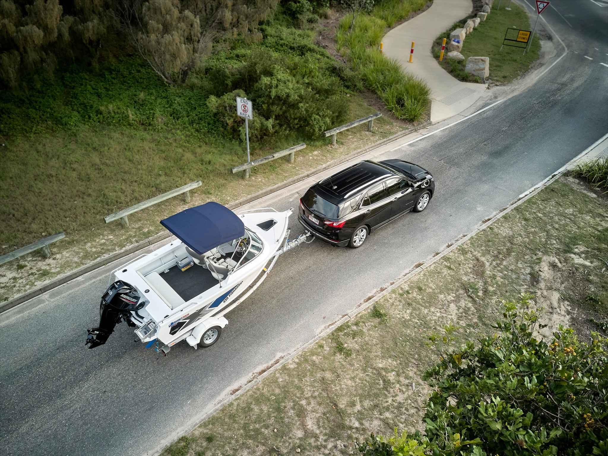 a boat and trailer being towed behind an SUV.