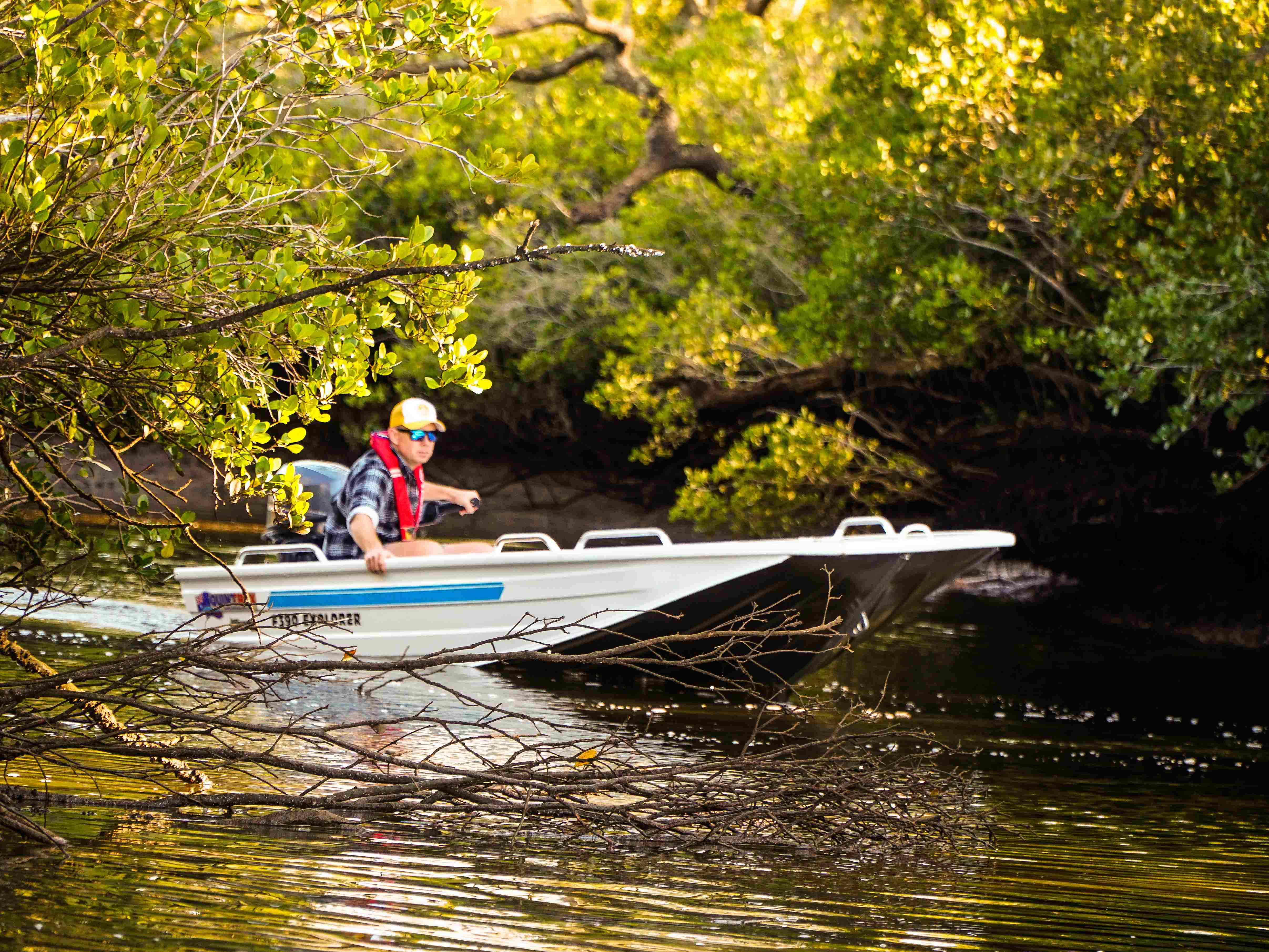 man on a quintrex tinny boat by the mangrove