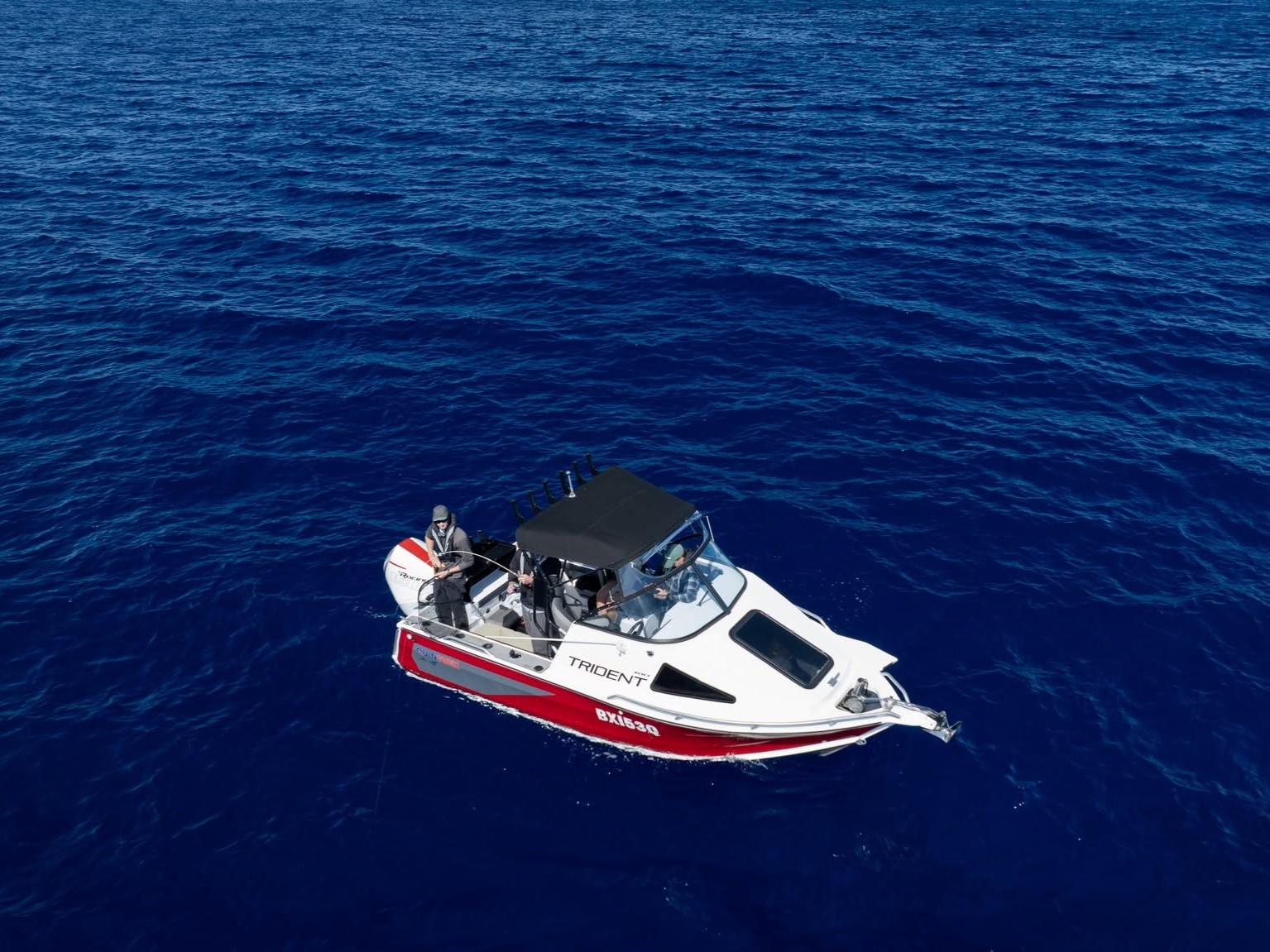 Two men fishing on a Quintrex Trident boat in the ocean.